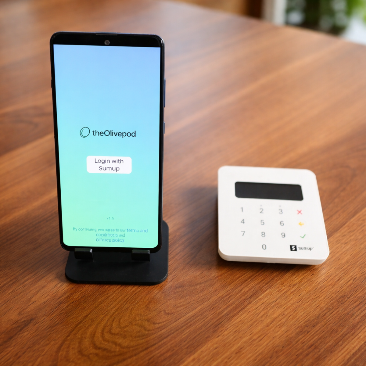 A DIY donation station featuring a smartphone running the OlivePod app, paired with a compact SumUp card reader on a countertop.